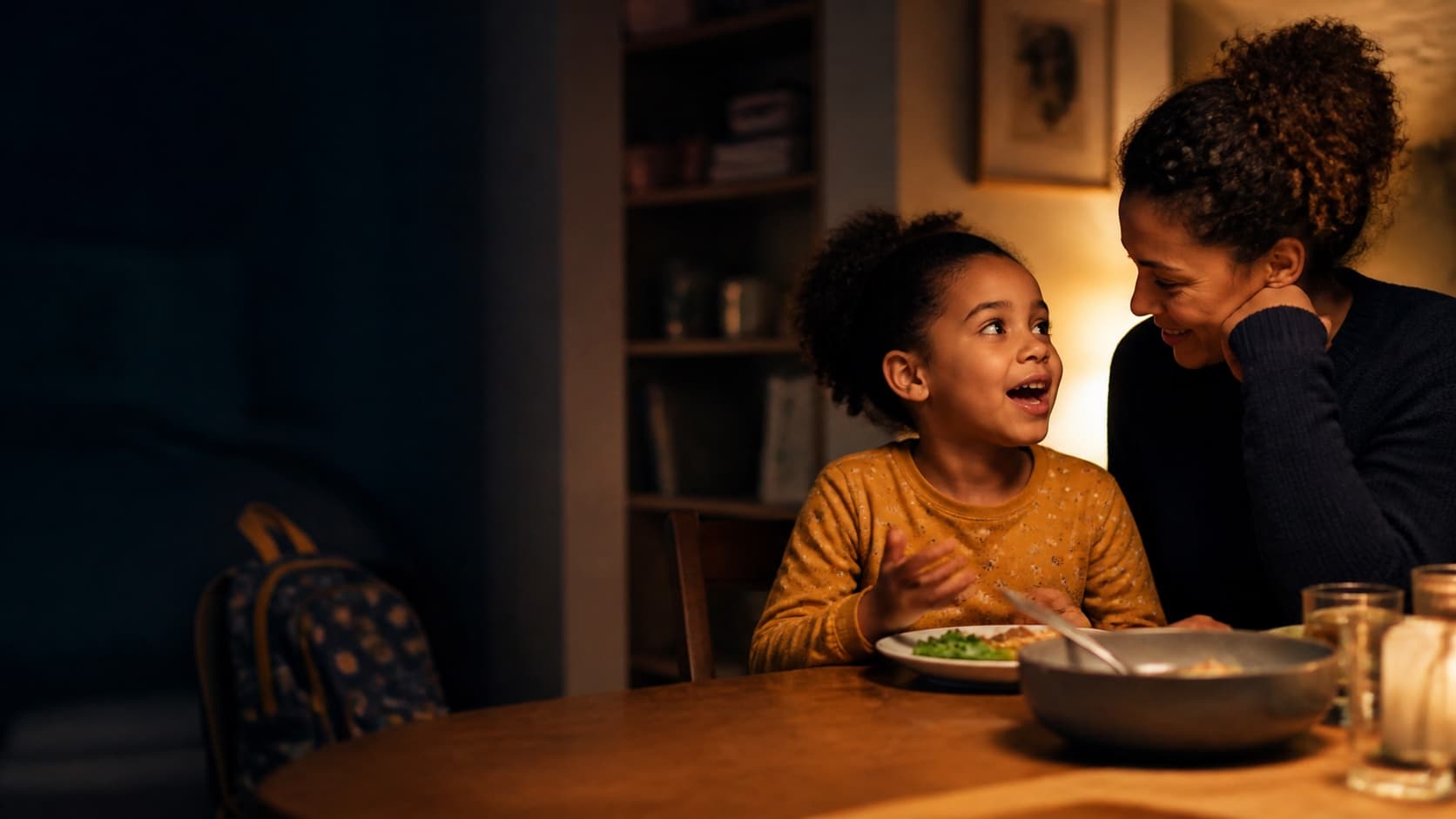 A child sharing an idea while a parent listens at the dinner table